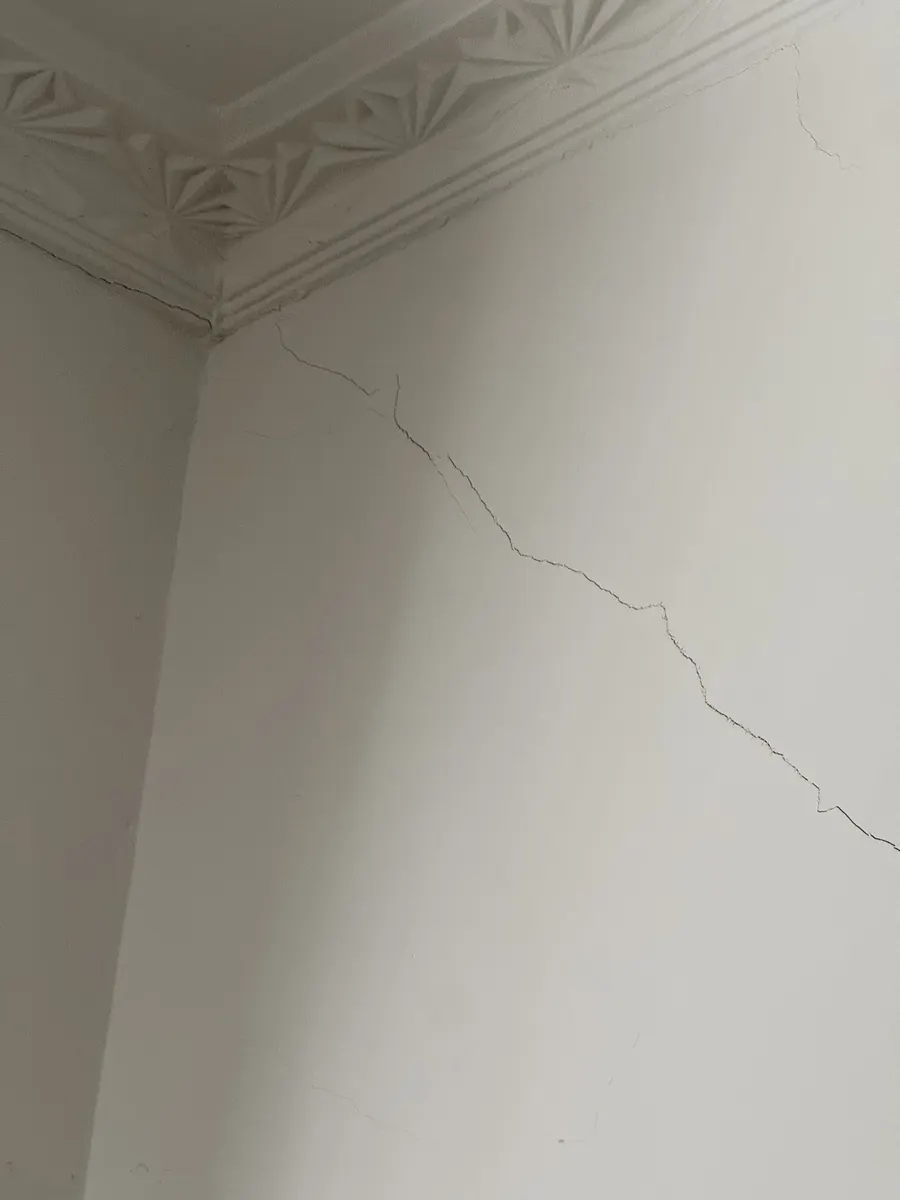 Diagonal plaster cracking running from the cornice, traced back to footing movement during inspection.